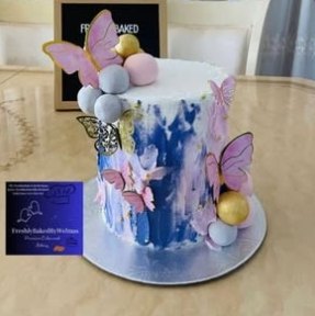 A painted blue cake with lilac butterflies and pearl spheres
