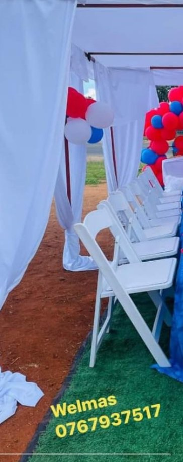 A white draped tent lined with white chairs and red and blue balloons