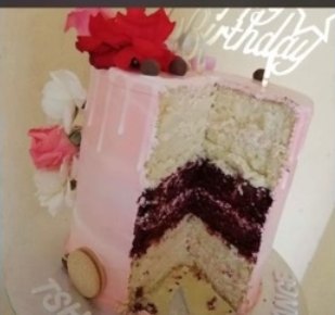 A sliced pink cake revealing red velvet and vanilla layers