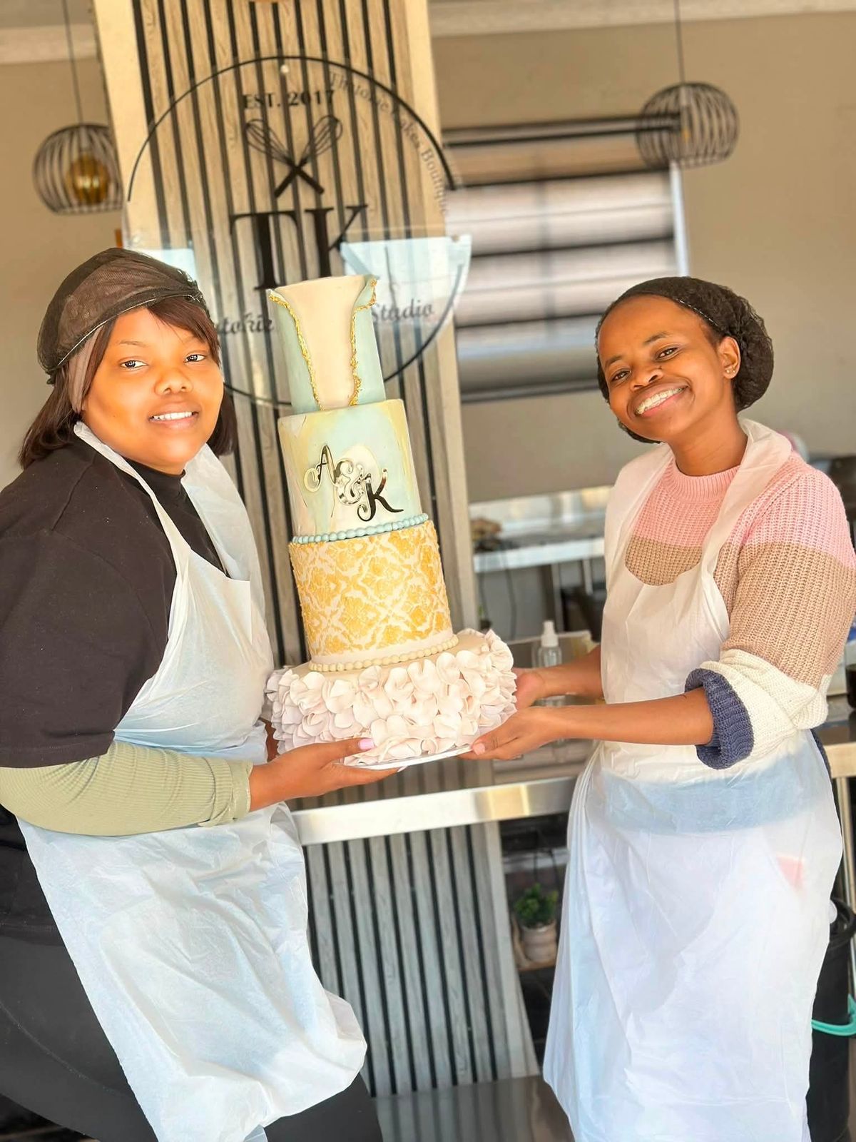 Lerato and her instructor holding the finished wedding cake